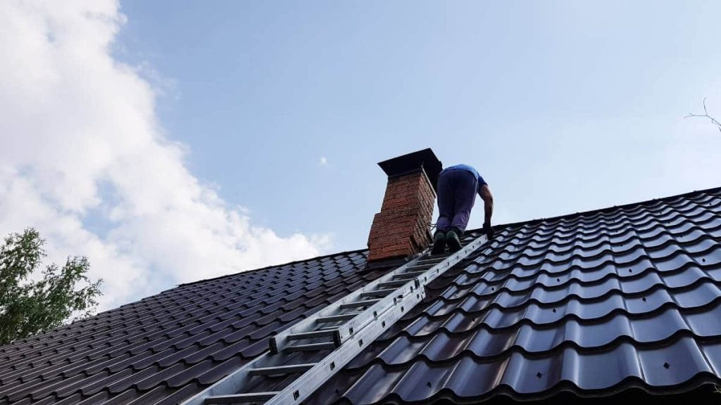 Schoorsteenveger klimt op de ladder naar het dak om de schoorsteen te vegen.